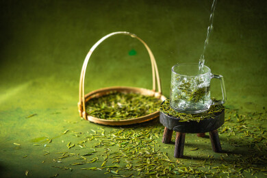 墨绿色桌面上有一些绿茶和茶杯
