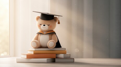 戴学位帽的泰迪熊坐在书堆上