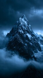 云雾缭绕下的深蓝色雪山峰顶