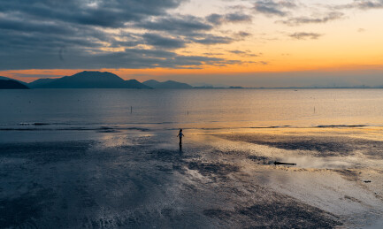 日落余晖映照滩涂海岸——宁静海景与人物剪
