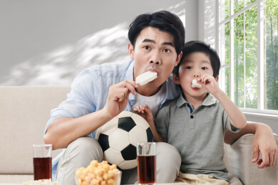 一对父子吃着冰棍看足球比赛