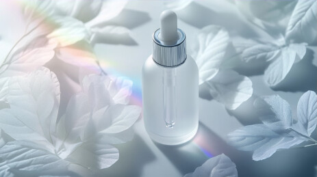 白色精油滴管瓶置于白色叶片与彩虹日光下