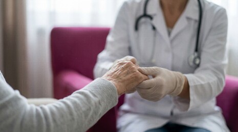 戴手套的医生紧握老人双手安慰