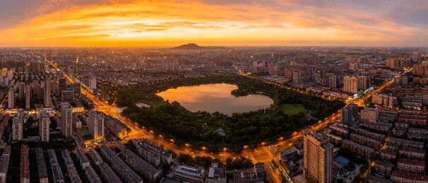 城市日落全景，中央有湖泊和绿地