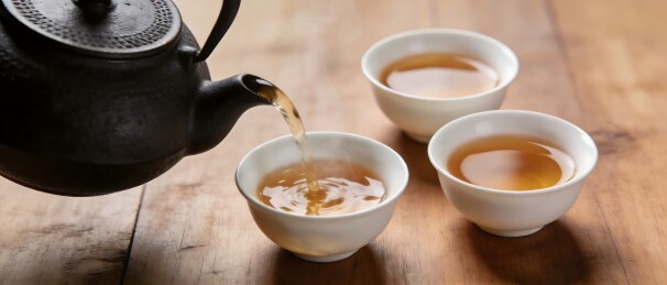 铁壶倒茶入杯木质桌面