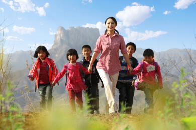 乡村女教师带领学生行走在山间小路上