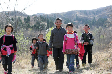 老师带领一群小学生在乡村山路上行走