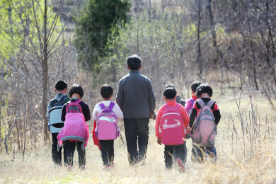 老师带领一群背着书包的小学生行走的背影