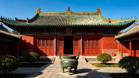 这是一座具有中国传统建筑风格的红色宫殿，屋顶为绿色瓦片，门前有一尊大鼎