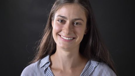 awomanwithshorthairsmilesandnodsagreeablyonablackbackground