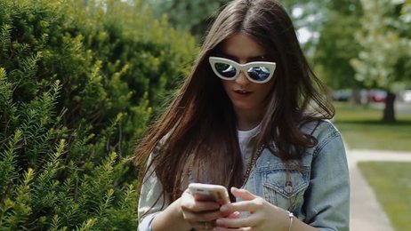 happywomansittingonthemeadowandusingtablet