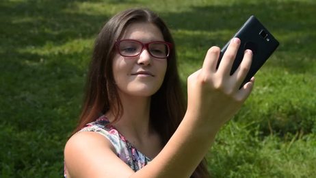 happywomansittingonthemeadowandusingtablet