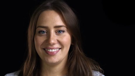 awomanwithshorthairsmilesandnodsagreeablyonablackbackground